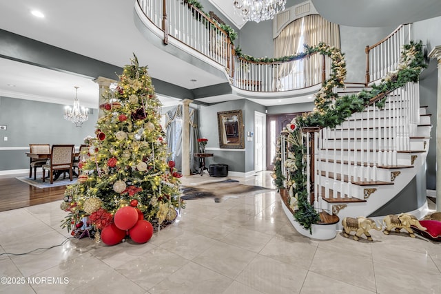 foyer entrance featuring crown molding, light tile patterned floors, a high ceiling, and an inviting chandelier