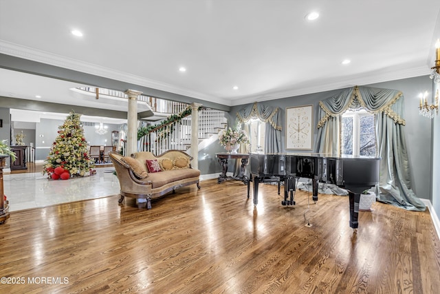 living area with hardwood / wood-style flooring, a notable chandelier, crown molding, and decorative columns