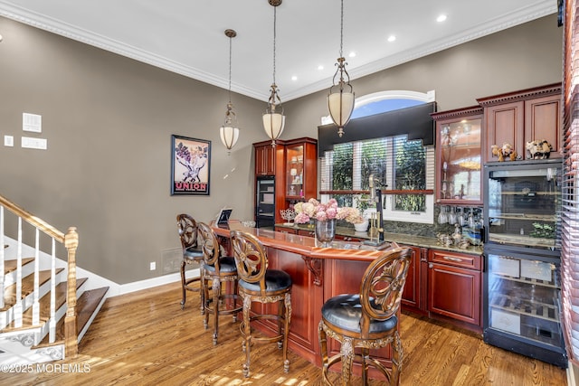 kitchen featuring decorative light fixtures, wine cooler, hardwood / wood-style flooring, and crown molding