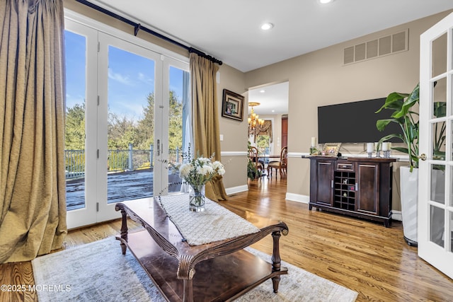 interior space featuring french doors, an inviting chandelier, a healthy amount of sunlight, and light hardwood / wood-style floors