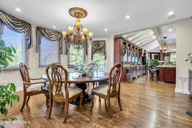 dining room with a chandelier, vaulted ceiling, and hardwood / wood-style flooring