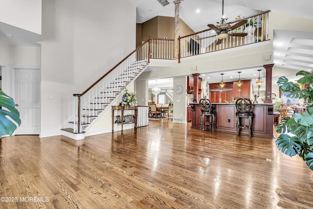 entrance foyer with hardwood / wood-style floors, ceiling fan with notable chandelier, and a towering ceiling