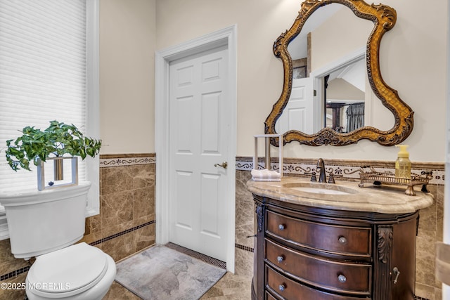 bathroom featuring vanity, toilet, and tile walls