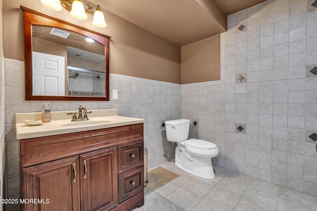 bathroom with vanity, tile patterned flooring, toilet, tile walls, and walk in shower