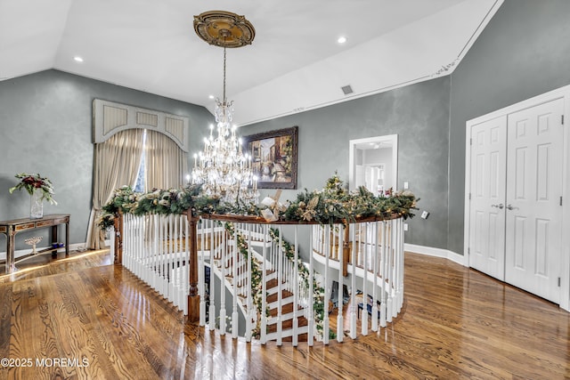 hallway featuring hardwood / wood-style floors, lofted ceiling, and a notable chandelier