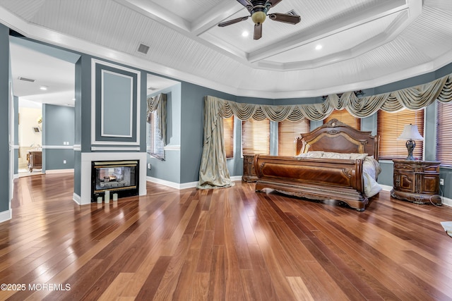 bedroom with a multi sided fireplace, hardwood / wood-style floors, crown molding, and coffered ceiling