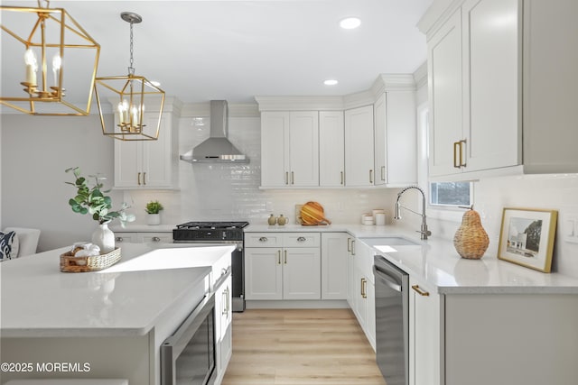 kitchen featuring stainless steel appliances, white cabinetry, wall chimney exhaust hood, a chandelier, and pendant lighting