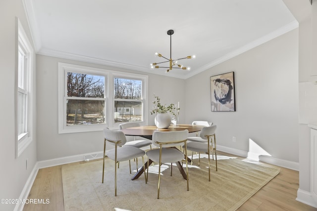 dining space featuring a notable chandelier, light wood-type flooring, and crown molding