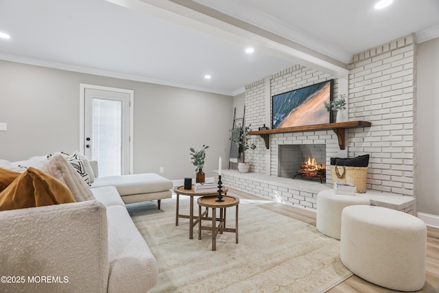 living room featuring a brick fireplace, ornamental molding, beam ceiling, and light hardwood / wood-style flooring