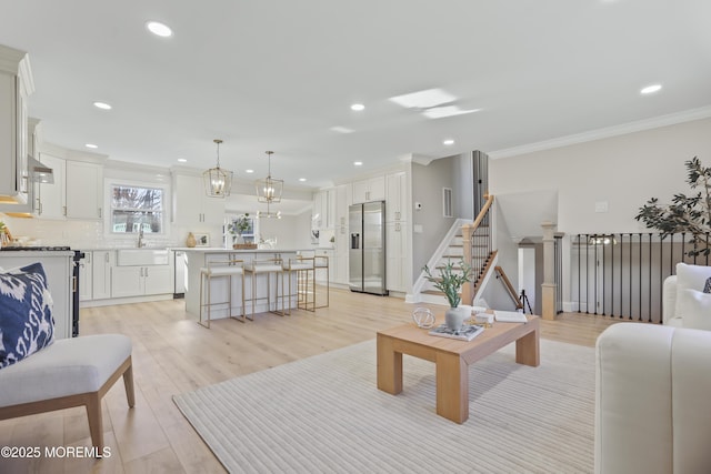 living room featuring light hardwood / wood-style floors, crown molding, and sink