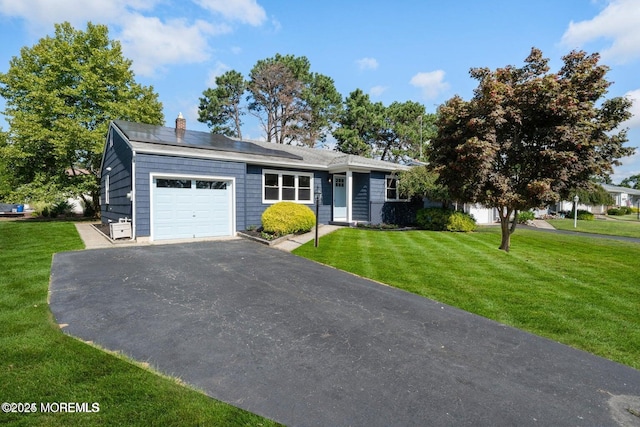 view of front of home with a front yard, solar panels, and a garage