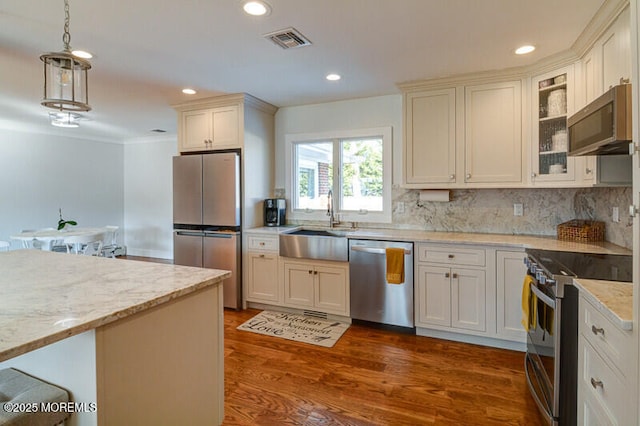 kitchen with pendant lighting, sink, light stone countertops, appliances with stainless steel finishes, and dark hardwood / wood-style flooring