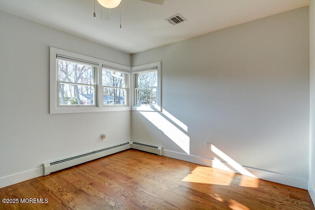 spare room with hardwood / wood-style flooring, ceiling fan, and a baseboard heating unit