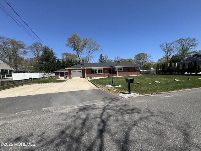 view of front of house featuring a garage, a chimney, a front yard, brick siding, and driveway