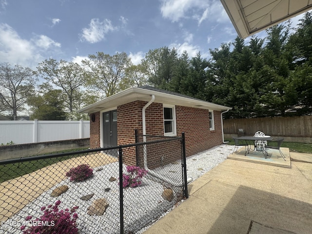 view of property exterior featuring a fenced backyard, a patio, outdoor dining space, and brick siding