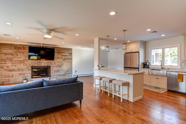 living room featuring recessed lighting, ceiling fan, visible vents, wood finished floors, and a fireplace