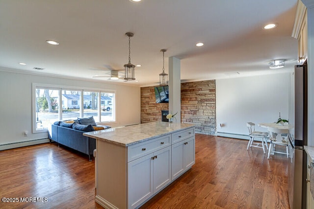 kitchen with a ceiling fan, a baseboard radiator, light stone countertops, decorative light fixtures, and open floor plan