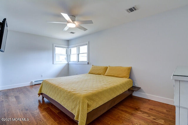 bedroom featuring visible vents, wood finished floors, baseboards, and a baseboard heating unit