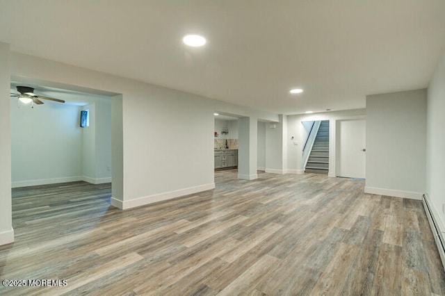 finished below grade area featuring baseboards, stairway, and wood finished floors