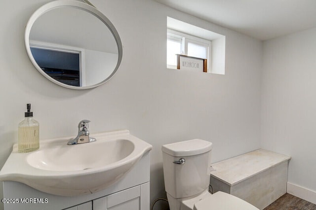 bathroom with toilet, baseboards, wood finished floors, and vanity
