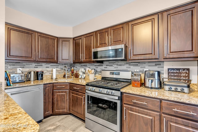 kitchen featuring sink, light stone countertops, and stainless steel appliances