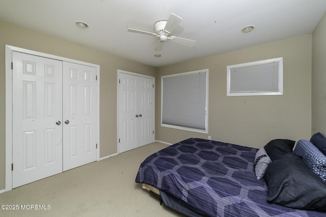 carpeted bedroom with ceiling fan and multiple closets