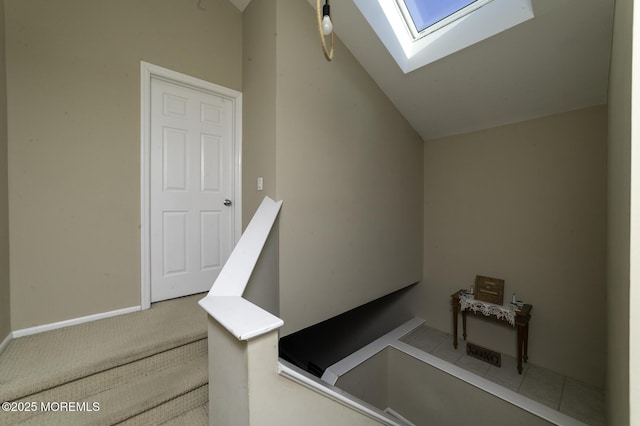 stairs featuring carpet and vaulted ceiling with skylight