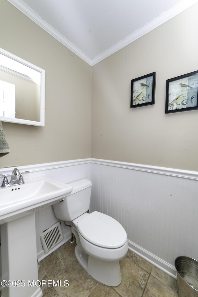 bathroom with tile patterned flooring, crown molding, and toilet