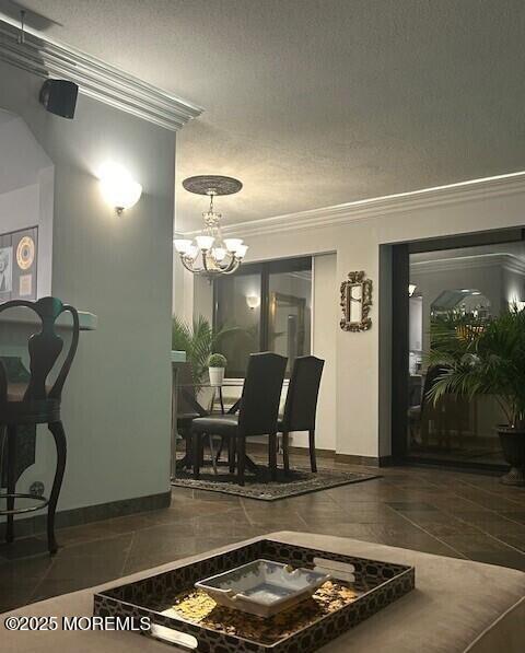 dining area featuring dark tile patterned flooring, an inviting chandelier, a textured ceiling, and crown molding