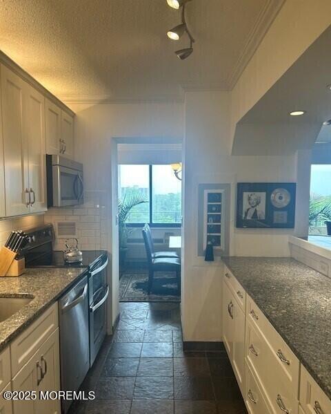 kitchen with stainless steel appliances, decorative backsplash, a wealth of natural light, and dark stone counters