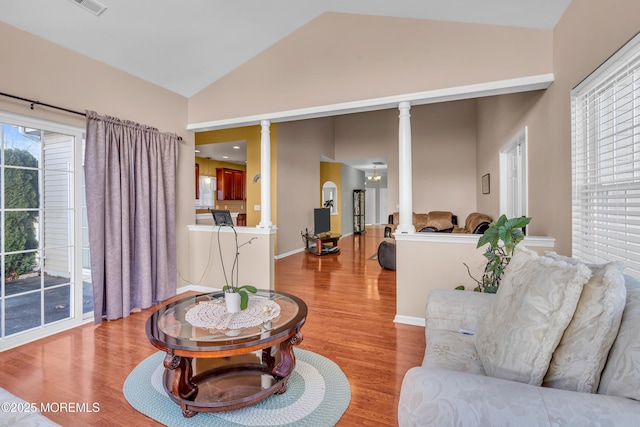 living room with vaulted ceiling, light hardwood / wood-style floors, and ornate columns