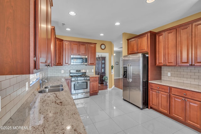 kitchen with decorative backsplash, sink, light stone countertops, stainless steel appliances, and light tile patterned floors