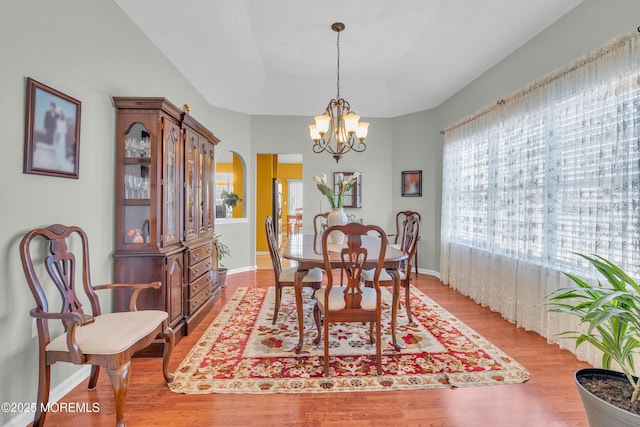 dining room with a chandelier, light hardwood / wood-style floors, and a raised ceiling