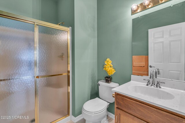 bathroom featuring a shower with shower door, toilet, and vanity