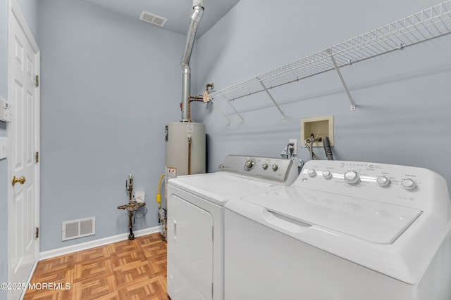 washroom featuring separate washer and dryer, light parquet floors, and gas water heater