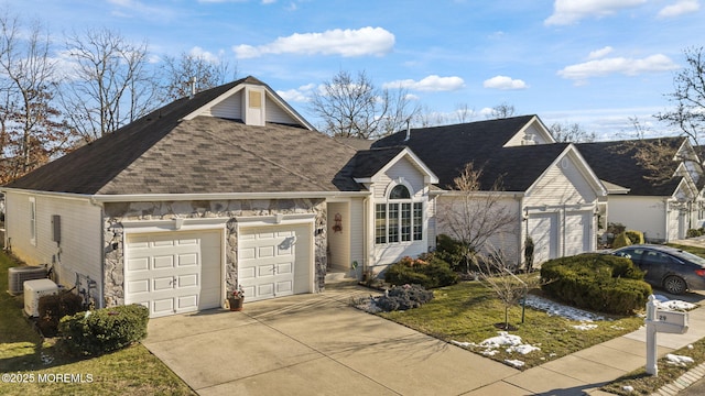 ranch-style house with a garage and central air condition unit