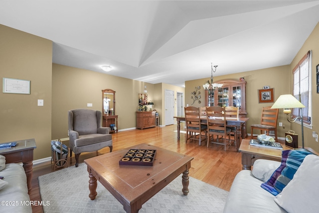 living room featuring lofted ceiling, light hardwood / wood-style floors, and a chandelier