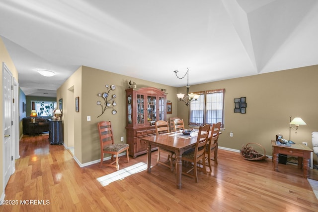 dining space with light wood-type flooring and a notable chandelier