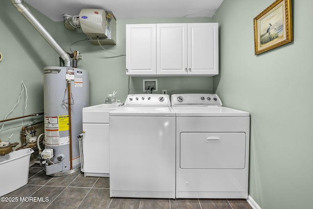 laundry area featuring water heater, dark tile patterned flooring, cabinets, and independent washer and dryer