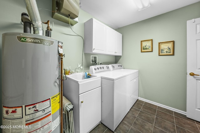 laundry area with washing machine and dryer, cabinets, dark tile patterned flooring, and gas water heater