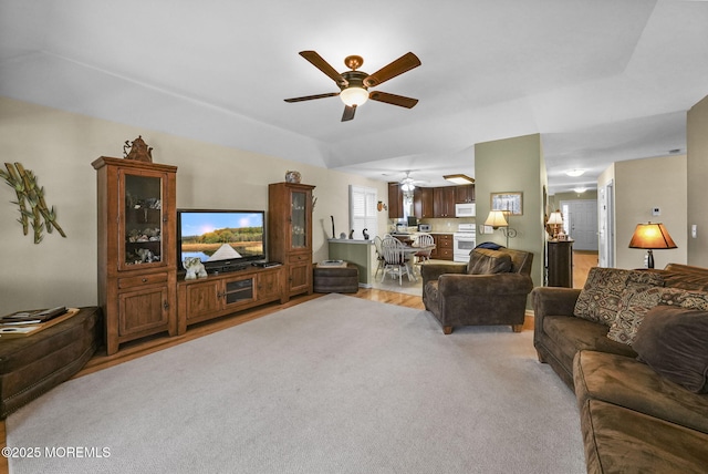 carpeted living room featuring a raised ceiling and ceiling fan