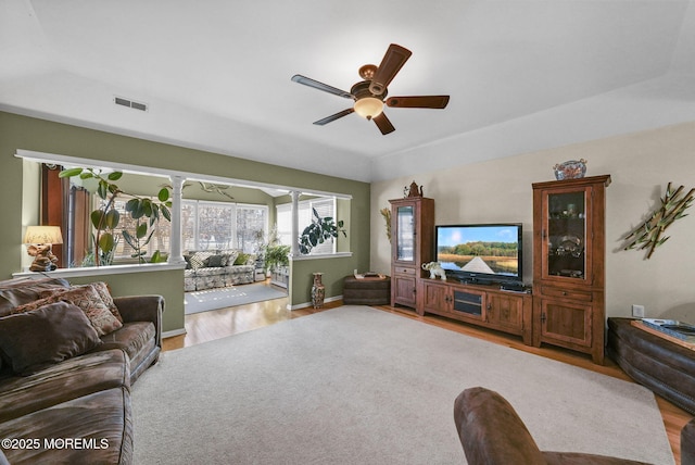 living room featuring ceiling fan, a tray ceiling, and wood-type flooring