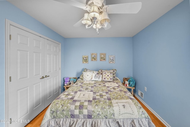 bedroom with ceiling fan, light hardwood / wood-style flooring, and a closet