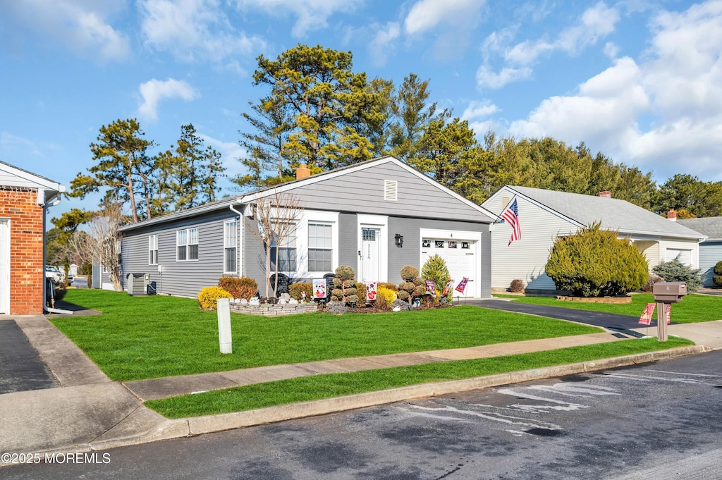 view of front of property featuring a front yard, a garage, and cooling unit