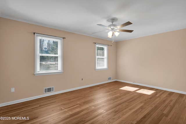 spare room with baseboards, visible vents, ceiling fan, and wood finished floors