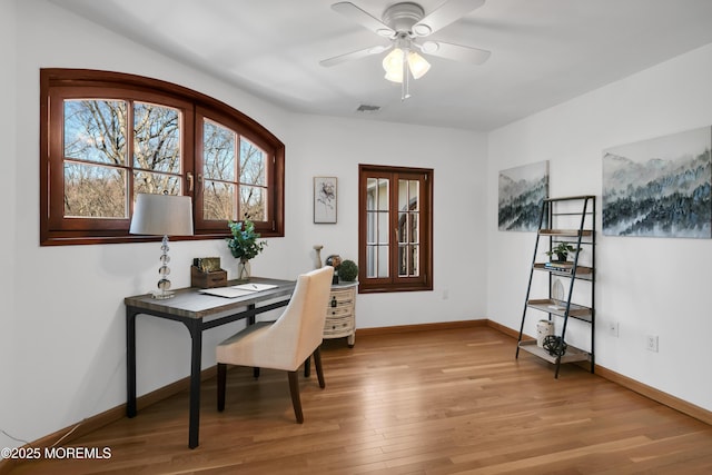 office featuring light wood-style flooring, visible vents, ceiling fan, and baseboards