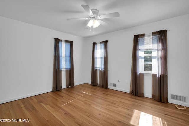 spare room featuring light wood finished floors, plenty of natural light, and visible vents