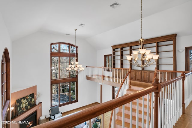 corridor with lofted ceiling, visible vents, and an inviting chandelier