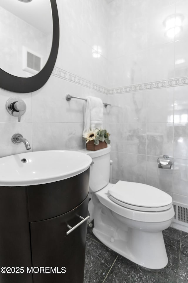 bathroom featuring toilet, visible vents, vanity, and tile walls