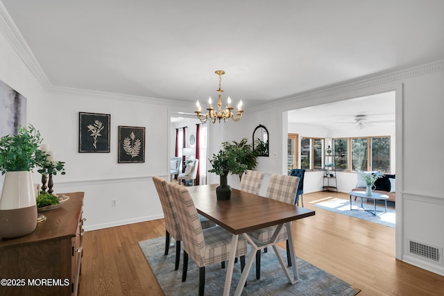 dining area featuring baseboards, visible vents, crown molding, and wood finished floors